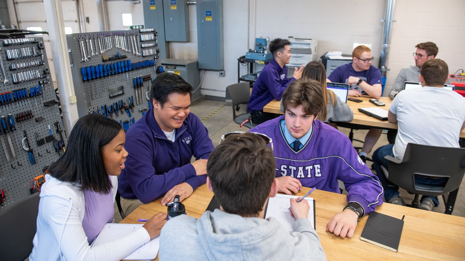 Engineering technology students sit in a lab discussing an assignment.
