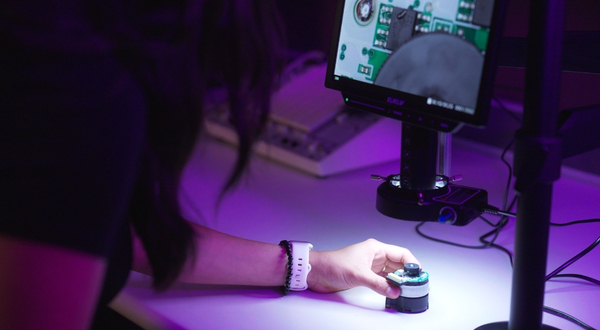 A student places a small piece or robotics software on a table next to a monitor that shows what's inside of the piece of equipment on the K-State Salina campus.