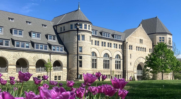 Photo from the exterior of Hale Library on the K-State Manhattan campus on a sunny day. In the foreground are beautiful purple flowers.