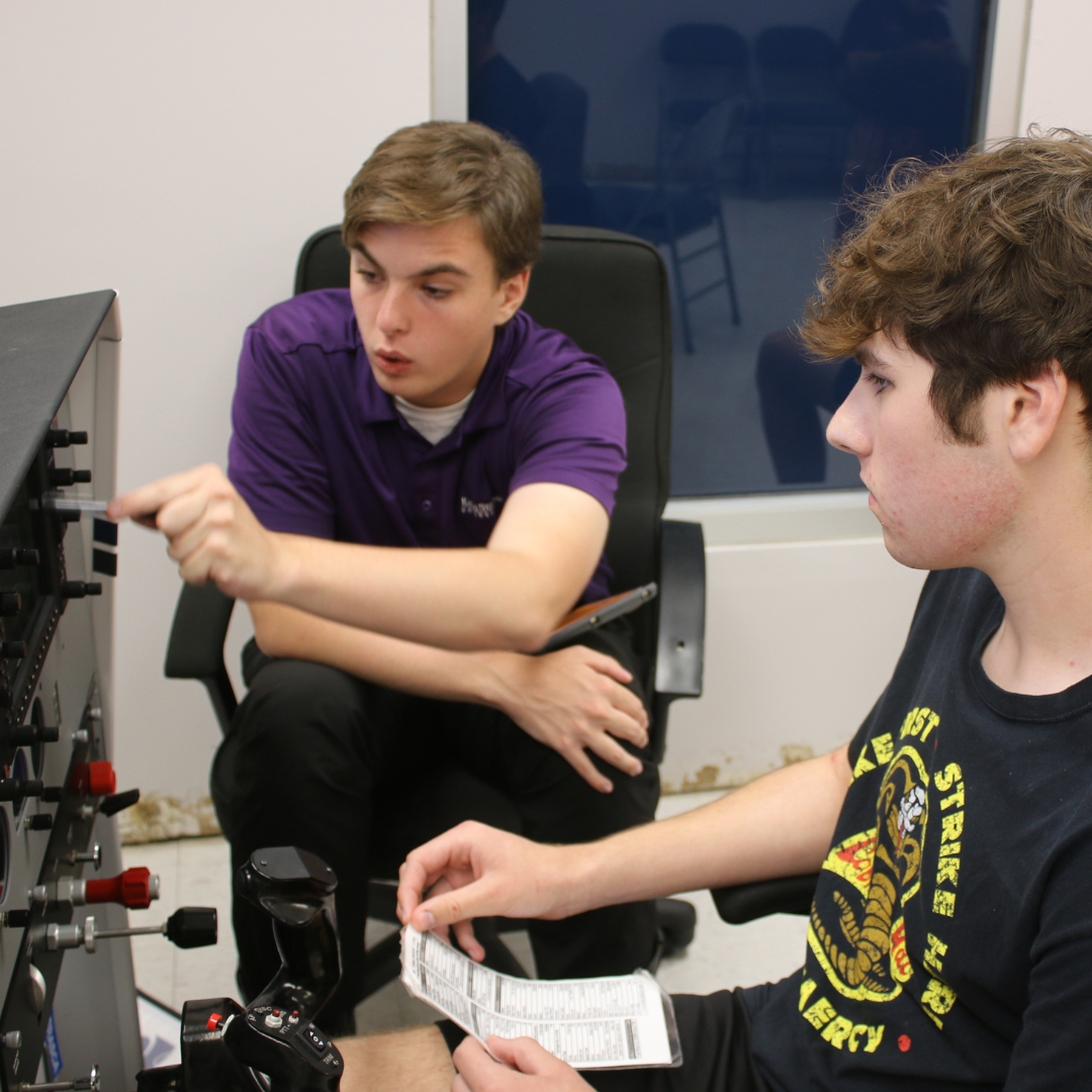A high school age student learns from an instructor while on a flight simulator. Students in K-State Salina's summer camps will have the opportunity to learn about K-State Salina's aviation simulators.