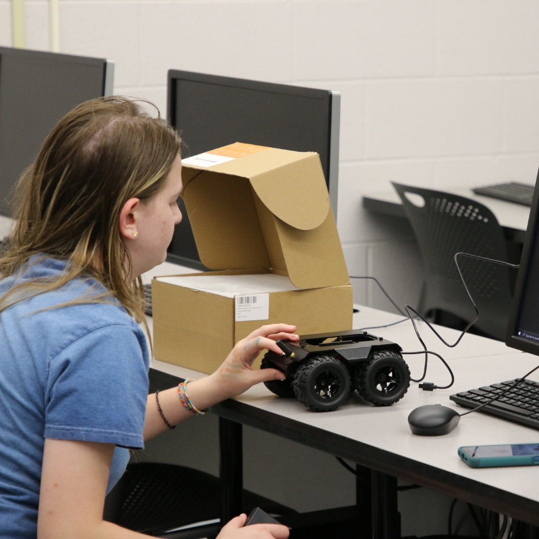 A student holds a robot that she created through K-State Salina's Robocats summer camp.