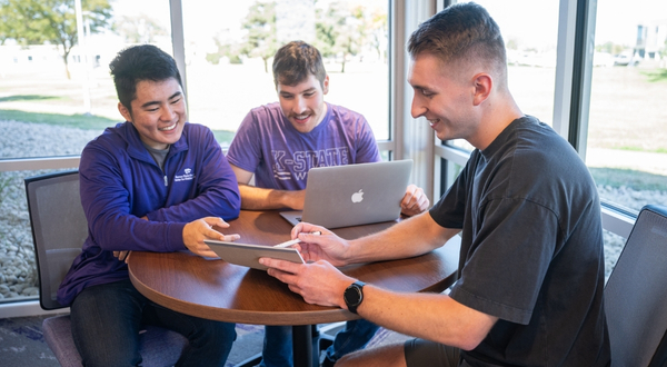 A group of K-State Salina students smile and talk with one another inside of the library.