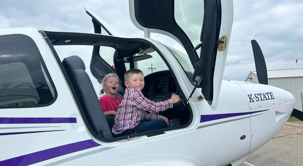 Two children excitedly explore an aircraft at the K-State Salina campus.