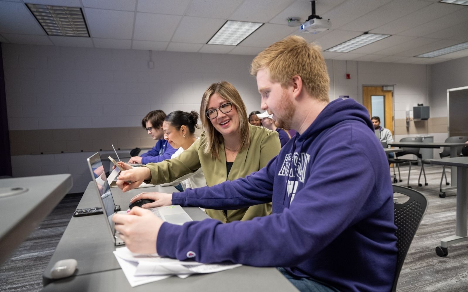 An instructor at K-State Salina helps a student during class as she points at the screen of a laptop to explain a concept to the student.