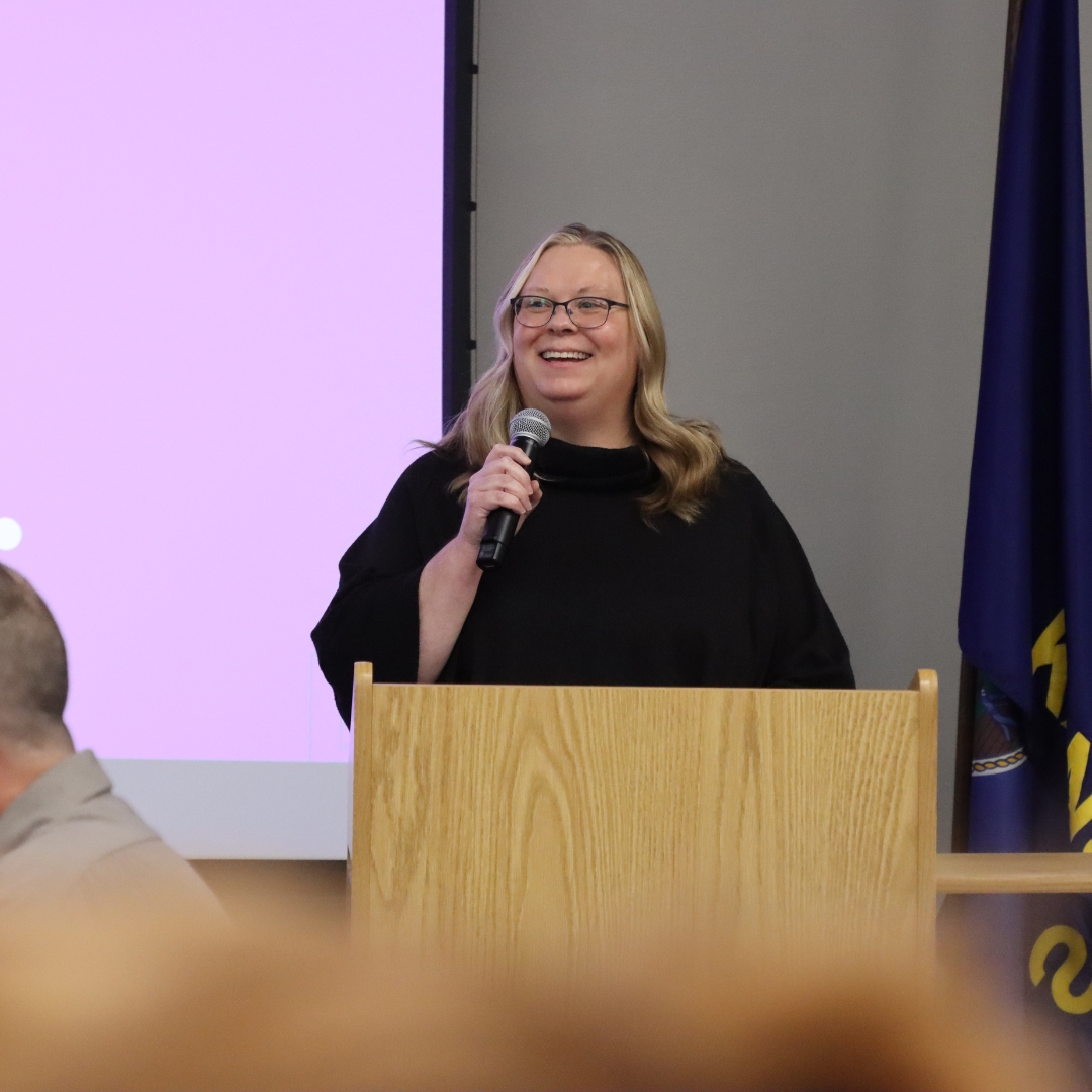 Alysia Starkey speaking into a microphone while smiling during a campus event.