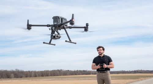 A learner holds a remote control operating a drone over an open field in K-State Salina's UAS training for professionals. 