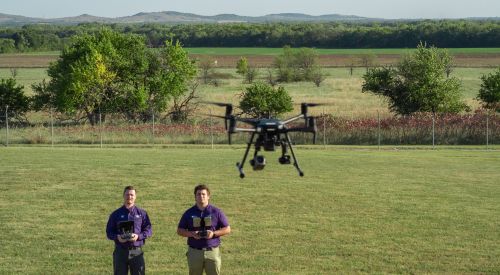 An instructor and learner fly a drone over an open field as apart of the K-State Salina's Professional Education and Outreach training.